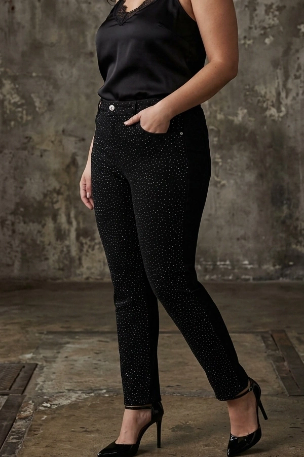 Plus size woman wearing black high waist rhinestone slim fit jeans with a black satin camisole and heels.