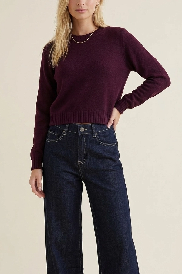 Woman wearing a burgundy cropped knit sweater with dark blue jeans
