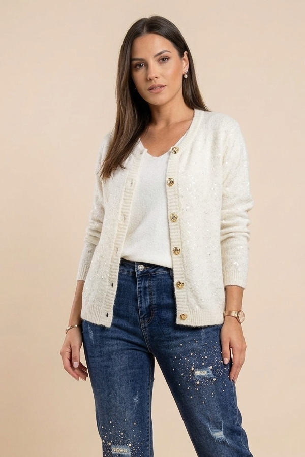 Woman wearing an ivory sequin cardigan with gold-tone buttons and blue jeans