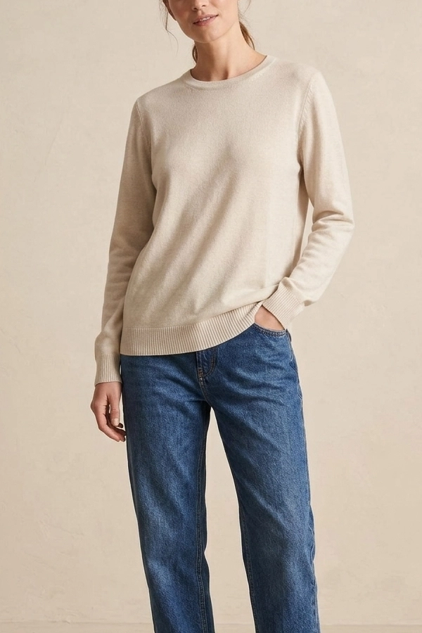 Woman wearing an ivory soft knit crew neck sweater with blue jeans.